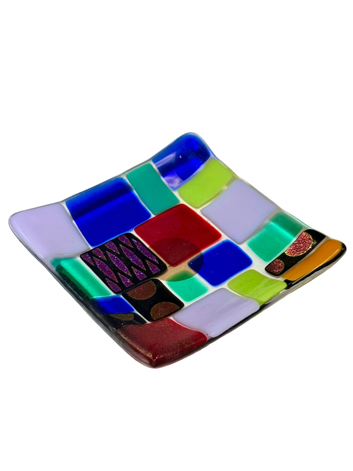 A square fused glass plate with rounded corners, featuring a colorful mosaic pattern of various colored squares on a plain off-white background.